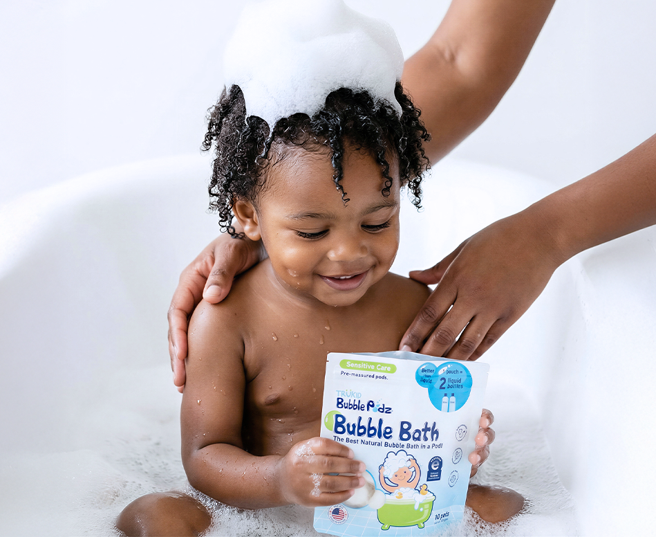 Child in a bubble bath with a pouch of Bubble Podz Bubble Bath, held by an adult.