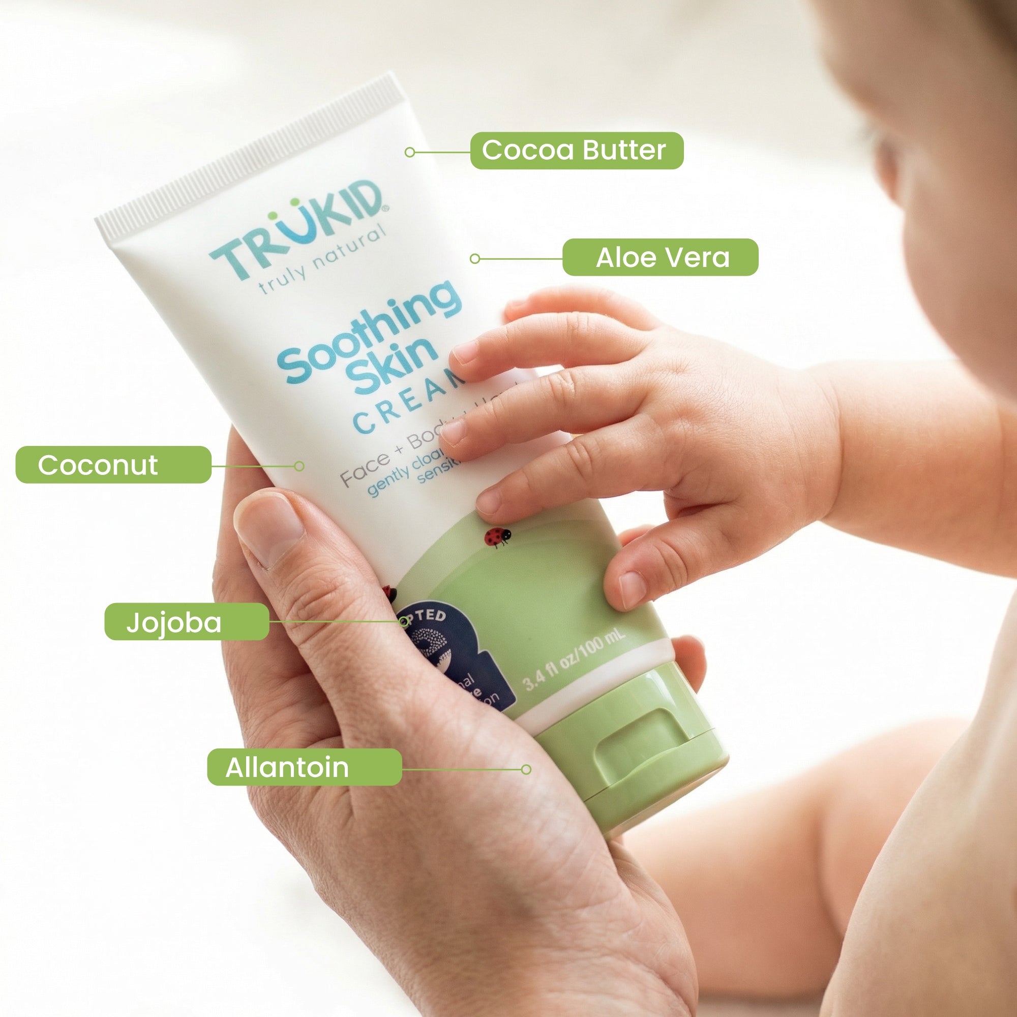 Trukid soothing skin cream with labeled ingredients and a baby's hand holding it.