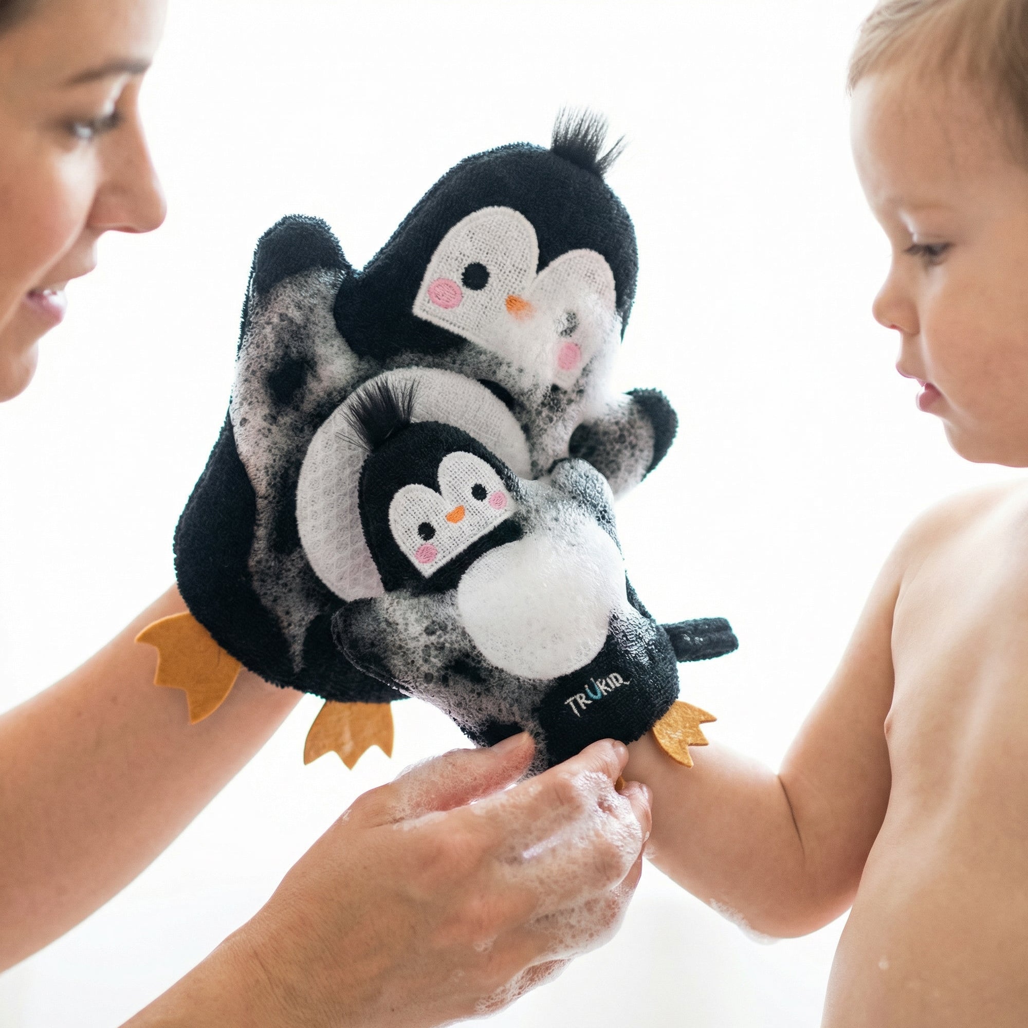 Person holding a penguin-themed glove with a child on a white background