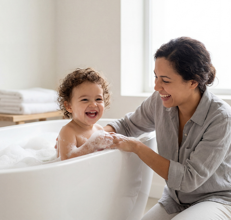 Woman and child in a bathtub with bubbles, laughing together.