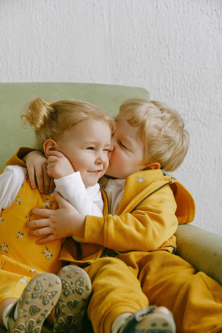 Two blonde kids hugging on a chair 