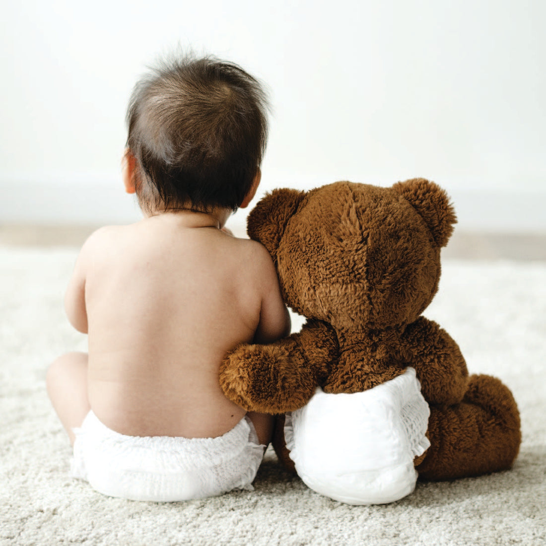 Baby and Stuffed bear hugging.